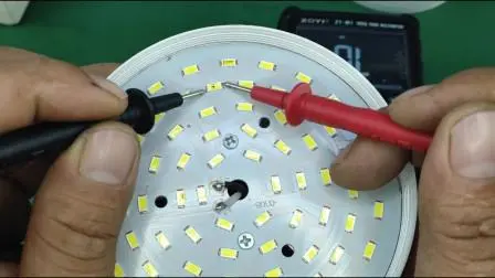 A Technician Using A Multimeter To Test The Connections Of An Led Light Fixture.