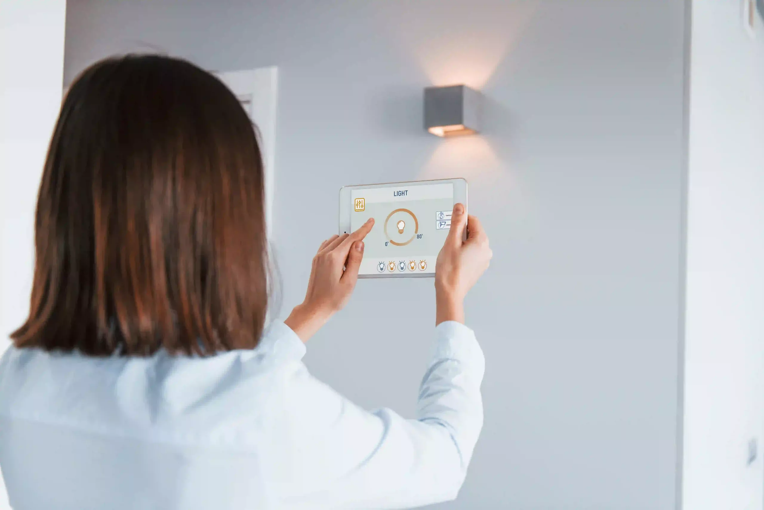 Rear View Of Woman That Is Indoors Controlling Smart Home Technology