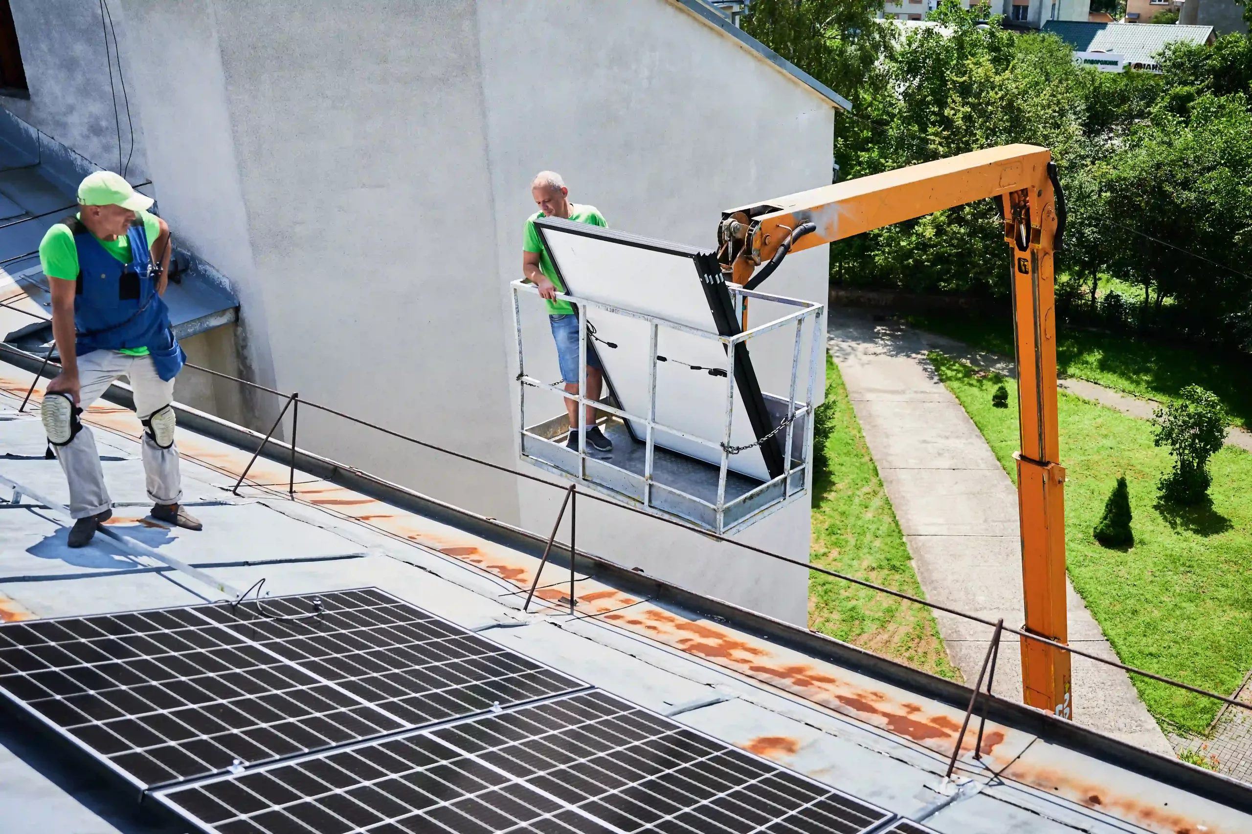 Workers Building Solar Panel System On Roof Of House. Installers Carrying Photovoltaic Solar Module