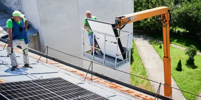 Craftsperson fastening solar panel components with an electric screwdriver.